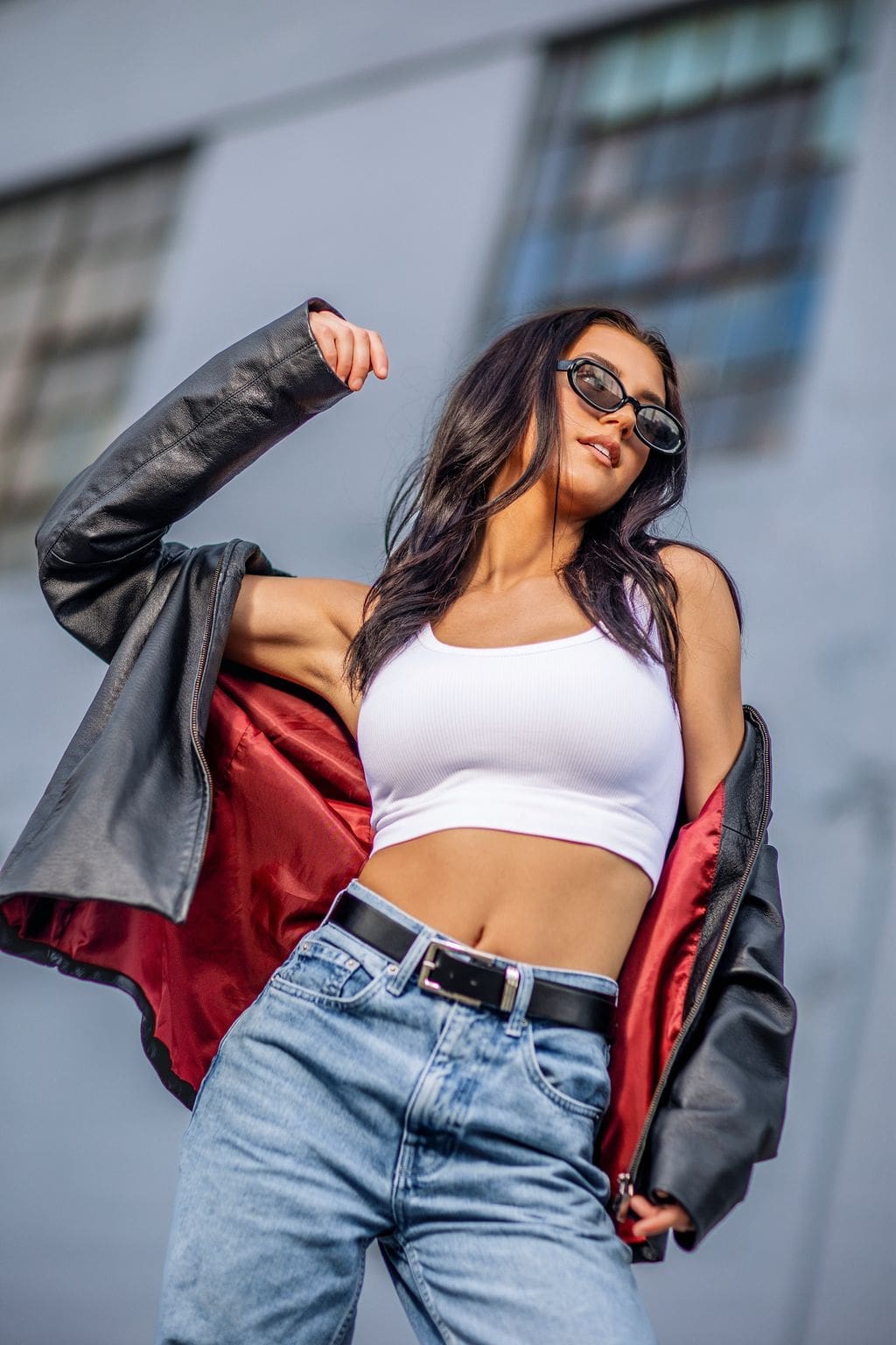 Fashion-inspired Indianapolis senior portrait of a senior girl wearing sunglasses, a black leather jacket, and jeans in an urban downtown setting.